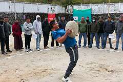 A man playing “Behgor”, lifting a large boulder and throwing it over his shoulder, one of the traditional Monpa games.