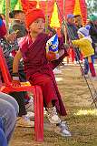 A very young novice monk watching the festival with the audience.