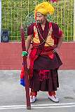 A monk with ceremonial headdresses and face paint to keep order with long staves, at the Torma ritual.