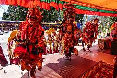 Masked dancers on the terrace of the monastery, with on the steps monks with ceremonial headdresses playing the Gya-Ling, a Buddhist ritual Reed Shawn.