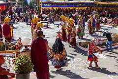 A spiritual dance, while monks with ceremonial headdresses play the Gya-Ling; with a monk filming.