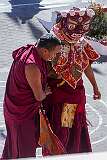 A masked dancer at the Drub-chod-Chen-Mo Torgya returns up the steps to the main hall of the monastery accompanied by a monk.