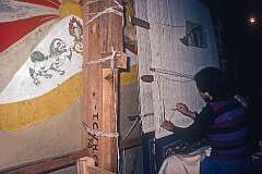 Weaving a carpet in a workshop at the Tibetan Children’s Village; at left the flag of Tibet.