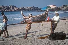 Fishermen pulling in their fishing net on the beach of Kovalam.