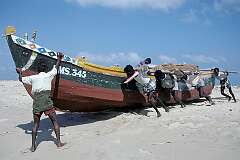 A wooden fishing boat being dragged to the sea on the beach in Dhanushkodi.