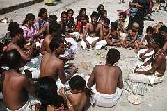 A “puja”, a Hindu ceremony that was requested by the seated men is performed by a priest at right; on the beach in Rameswaram.