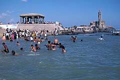 Tourists having a swim in Kanniyakumari, at Cape Comorin. In the background the Vivekananda Memorial and the statue of the poet Thiruvalluvar.