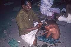 A young boy having his head shaved: a dedication to the god Shiva.