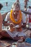 A man with Shiva sign and a flower garland besides the Ganges river, Varanasi.