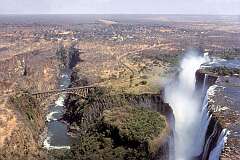 The mighty Victoria Falls or Mosi Oa Tunya ("The smoke that thunders") on the border of Zimbabwe and Zambia, with the Victoria Falls Bridge, built in 1905.
