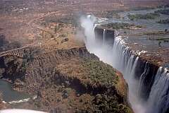 Mosi Oa Tunya ("The smoke that thunders"), the Victoria Falls on the border of Zimbabwe and Zambia, with the 1905 Victoria Falls Bridge over the gorge, seen from the Zambian side.